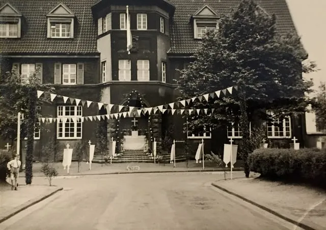 Das Jugendhaus auf einem alten Schwarz-Weiß-Foto: dunkle Fassade, mit Wimpelketten und Fahnen geschmückt.